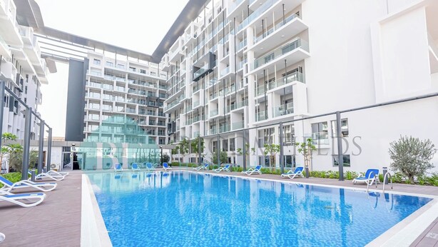 A modern hotel with a swimming pool, sun loungers, and a glass facade. - Bloomfields Fantastic STU in Oasis Masdar City (Abu Dabi)