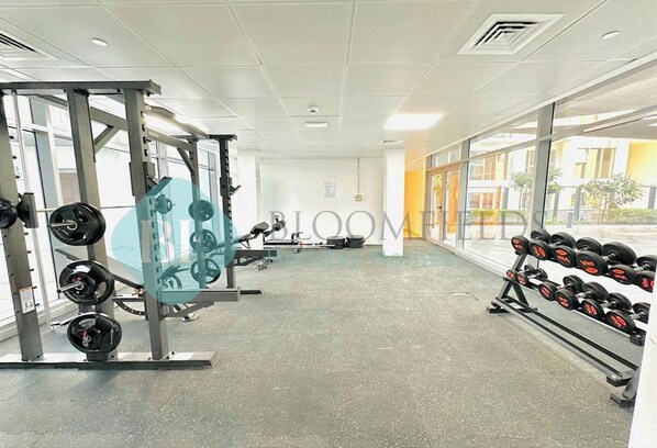 A gym with weightlifting equipment, a squat rack, and dumbbells.