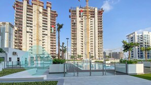 A modern residential complex with high-rise buildings, a swimming pool, and landscaped areas. - Bloomfields Modern STU In Azizi Riviera (Dubai)