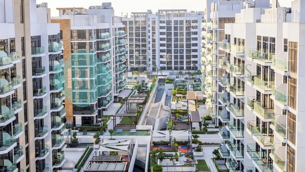 A modern high-rise residential building with multiple balconies, a central courtyard, and a mix of glass and concrete facades. - Bloomfields Modern STU In Azizi Riviera (Dubai)