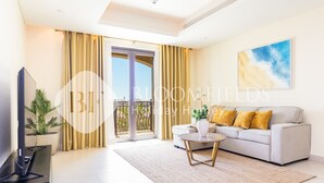 A modern living room with a sofa, coffee table, and TV. - Bloomfields 1BR St Regis in Saadiyat (Abu Dhabi)