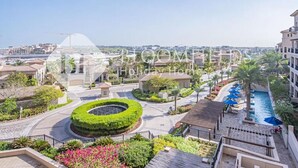A residential area with a circular garden, a swimming pool, and a view of the cityscape. - Bloomfields 1BR St Regis in Saadiyat (Abu Dhabi)