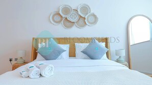 A neatly made bed with white linens, two pillows, and a set of towels. - Bloomfields Adorable 1BR in Raha Beach Access (Abu Dabi)