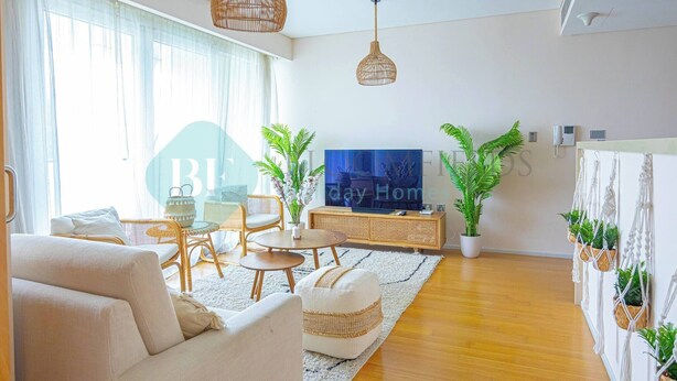 A modern living room with a sofa, coffee table, TV, and potted plants. - Bloomfields Adorable 1BR in Raha Beach Access (Abu Dabi)