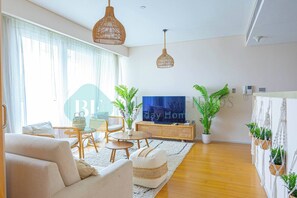 Una sala de estar moderna con un sofá, una mesa de centro, televisor y plantas en macetas.