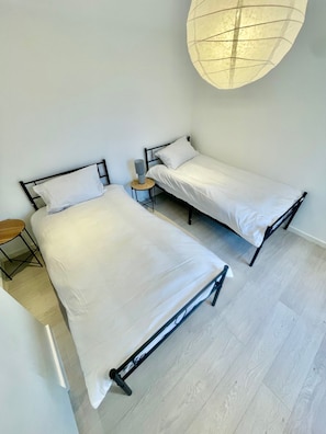 A room with two beds, a small table, and a hanging light fixture. - Cambridge Cozy 2 Bedroom Apartment 5 Sleep (Cambridge)