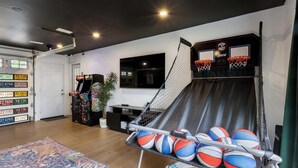 Uma quadra de basquete particular, com rede, uma televisão presa na parede e uma porta com abertura automática.