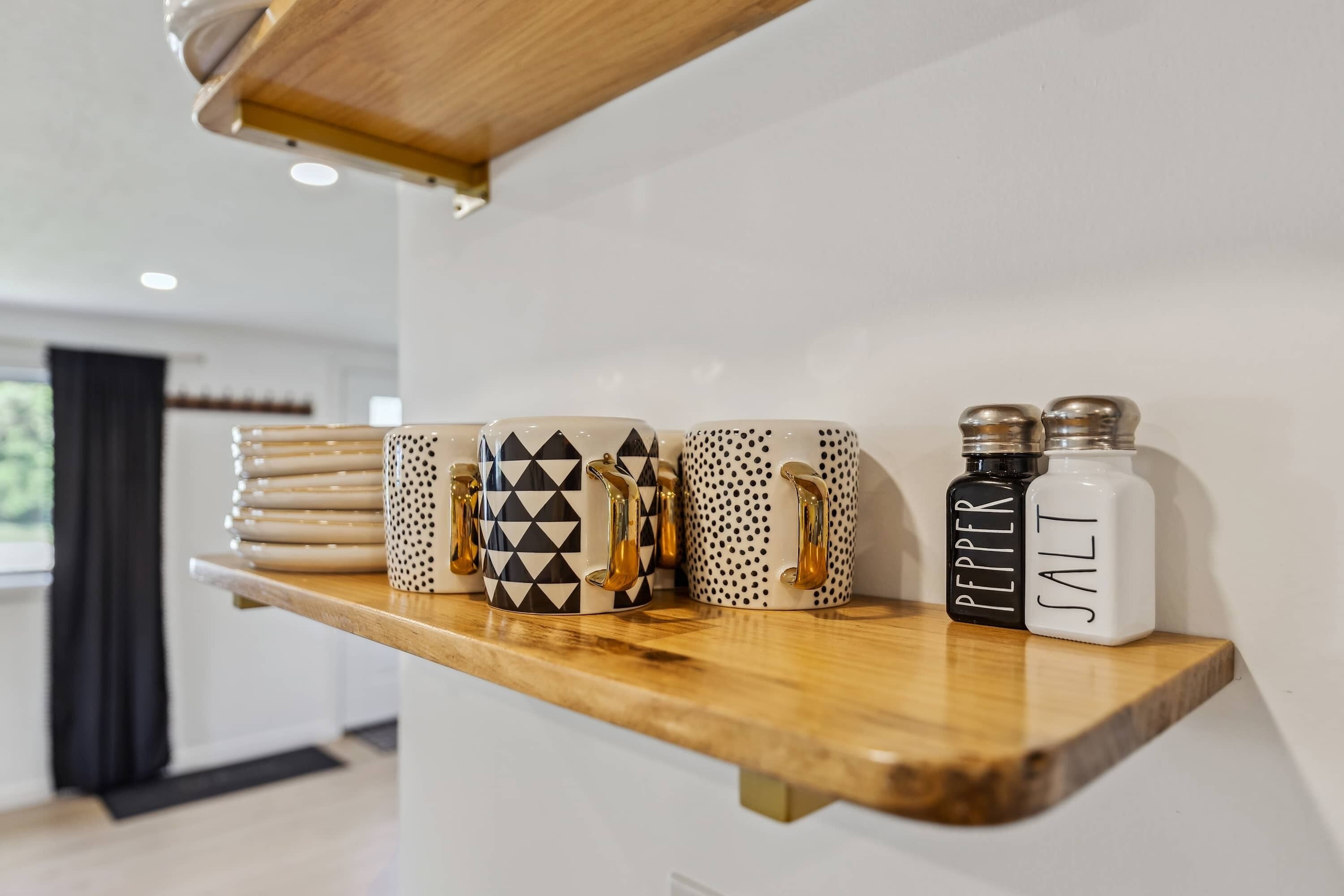 Une étagère de cuisine avec différentes tasses et des salières et poivrières.