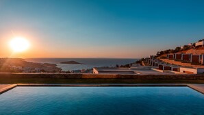 Una piscina con vista al mar y edificios al atardecer.
