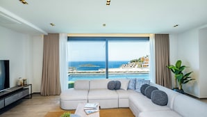 Una sala de estar moderna con un ventanal grande, un sofá modular, una mesa de centro y un televisor sobre un mueble bajo.