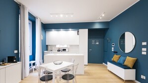A modern kitchen with white cabinets, a white dining table with chairs, and a built-in microwave. - Easylife: Elegant with Terrace near Centrale FS (Milano)