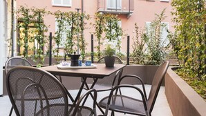 An outdoor seating area with a table and chairs, surrounded by plants and a building with balconies. - Easylife: Elegant with Terrace near Centrale FS (Milano)