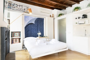 Un dormitorio con cama, un mural del cielo nocturno, una mesita de noche con lámpara y un armario blanco.