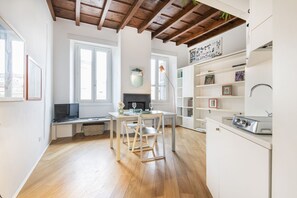 Uma cozinha moderna com piso de madeira, uma área de jantar com mesa e cadeiras, e uma estante embutida.