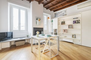 Una sala de estar moderna con televisor, chimenea, mesa de comedor y estantería.