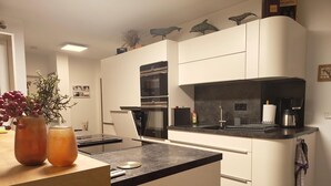 A modern kitchen with white cabinets, a black countertop, and a built-in oven. - Marina-Penthouse 625 - Spacious vacation apartment on 1 level with harbor view. (Rechlin-Nord)
