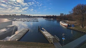 A river with a boat docked on the right, a lock system in the middle, and buildings along the riverbank. - Marina-Penthouse 625 - Spacious vacation apartment on 1 level with harbor view. (Rechlin-Nord)