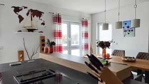 A modern kitchen with a black countertop, a wooden island with a knife block, and a world map on the wall. - Marina-Penthouse 625 - Spacious vacation apartment on 1 level with harbor view. (Rechlin-Nord)