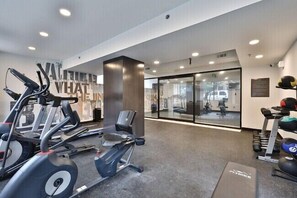 A modern gym with cardio equipment, a wall with motivational text, and a glass wall offering a view of the outside. - Fairfax Apartments 425 Spacious 1 Bed 1 Bth (Philadelphia)