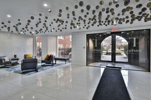 A modern lobby with a reflective floor, seating area with sofas and a bench, and a glass entrance with a view of the outside. - Fairfax Apartments 425 Spacious 1 Bed 1 Bth (Philadelphia)