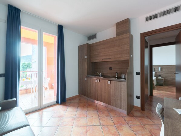 A modern kitchen with wooden cabinets, a sink, and a stove. There is a sliding glass door leading to a balcony with a table and chairs. - Residence Near the sea a Loano 4202 (Loano)