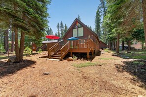 Une cabane dotée d’une terrasse en bois et d’un escalier menant à une véranda couverte.