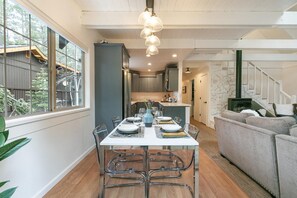 A modern kitchen with a dining area, a staircase, and a living room.