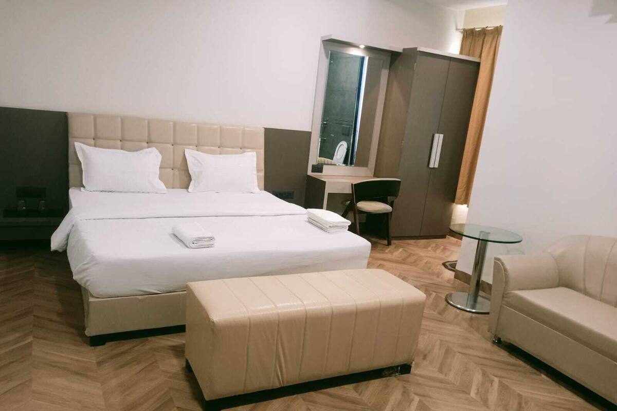 A hotel room with a large bed, a small table, a chair, and a sofa.