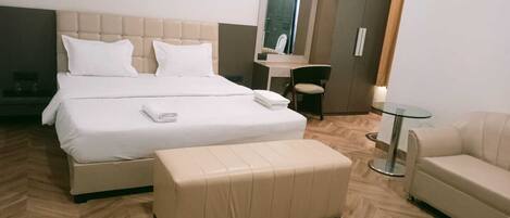 Une chambre d’hôtel avec un grand lit, une petite table, une chaise et un canapé.