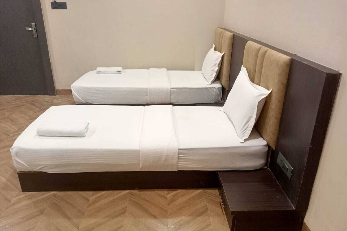 A double bed with a wooden headboard and a small wooden bench beside it.