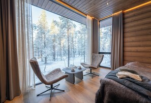 A modern room with large windows, two chairs, a small table, and a sofa. - Wilderness Hotel Saariselkä (Saariselka)