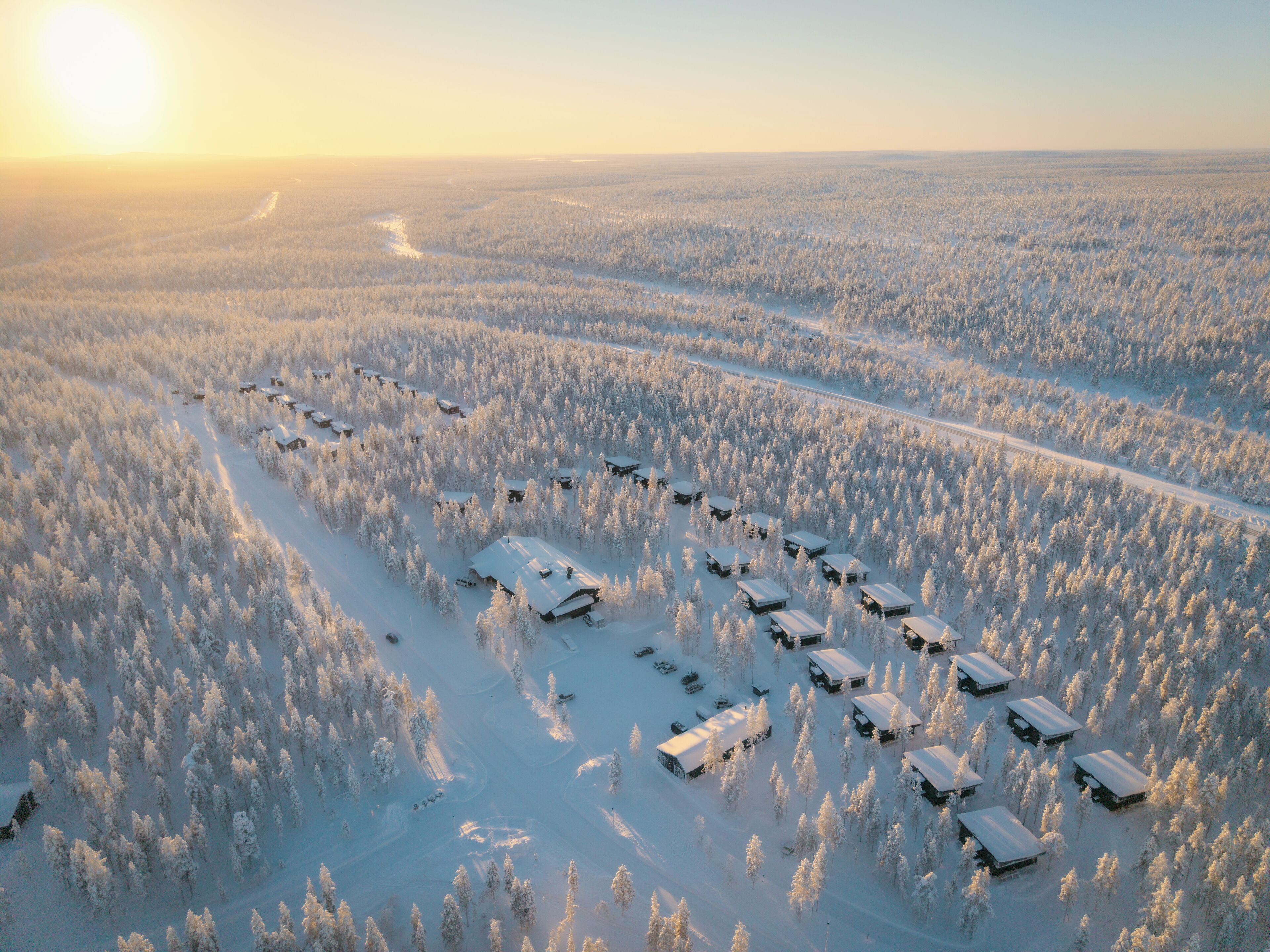 Lumipeitteisen metsän ilmakuvassa näkyy useita mökkejä, jotka on asetettu riviin.
