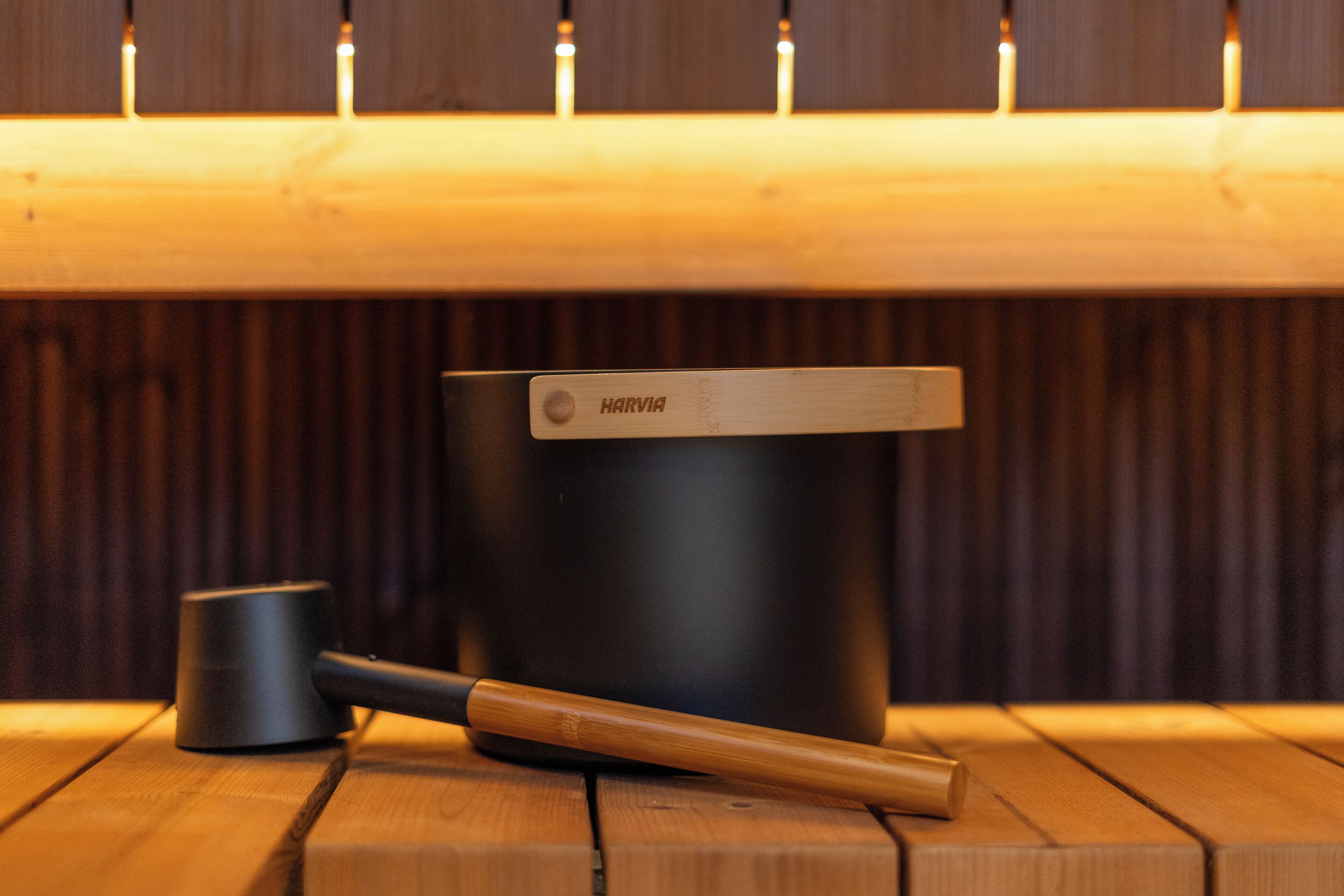 Una mesa de madera con un recipiente negro etiquetado 'HARVIA' y un mazo de madera encima.