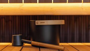 Una mesa de madera con un recipiente negro etiquetado 'HARVIA' y un mazo de madera encima.
