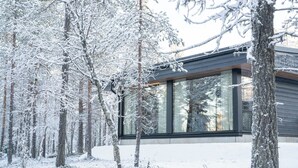 Een modern gebouw met grote glasramen, omgeven door een besneeuwd bos.