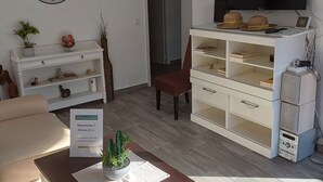 Un soggiorno con divano, tavolino con una pianta, televisore e libreria.