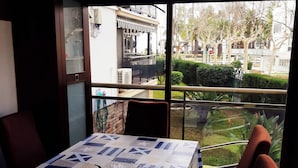 Zona pranzo con tavolo ricoperto da una tovaglia fantasia, sedie e vista esterna.
