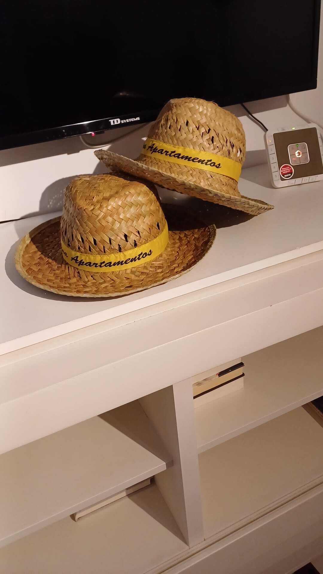 Two woven hats with yellow bands on a white surface.