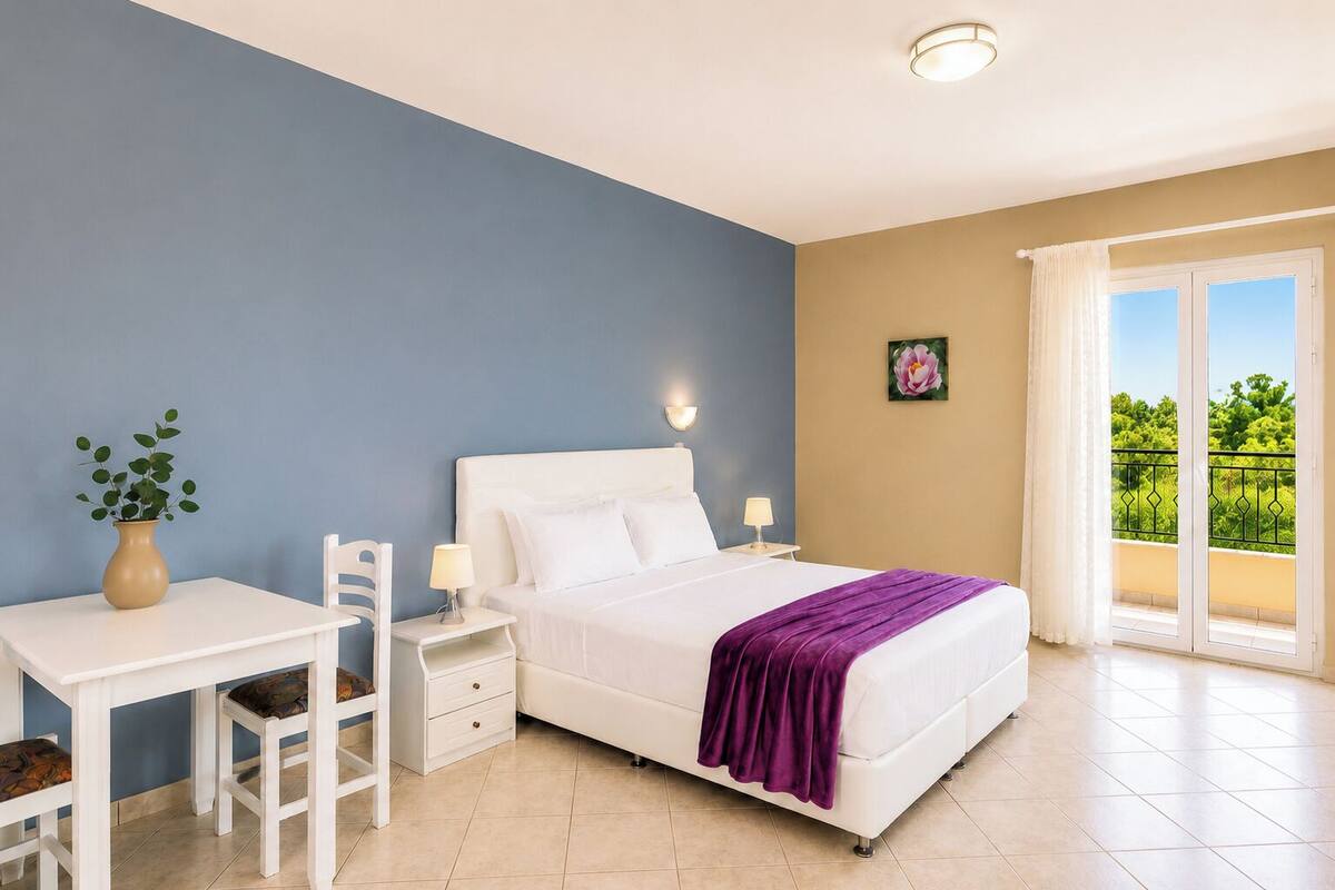 Une chambre à coucher avec un lit, des tables de chevet, une chaise, un bureau, un vase avec une plante et un balcon avec vue.