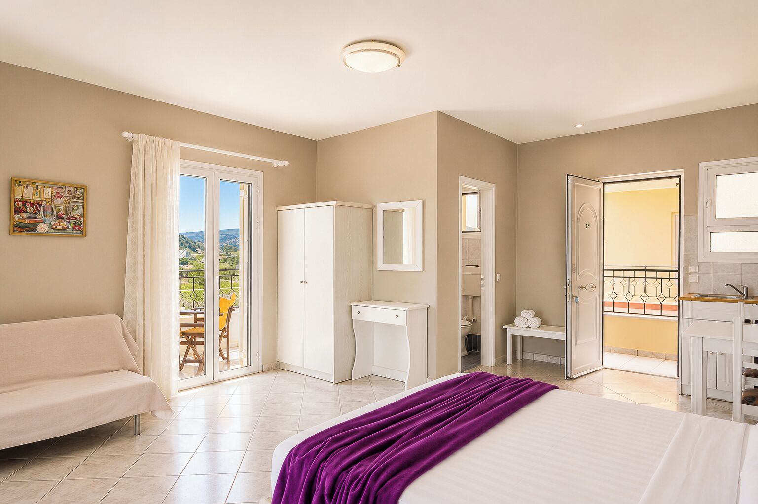 Une chambre d’hôtel comprenant un lit, un bureau, une armoire, une salle de bain et un balcon avec vue.
