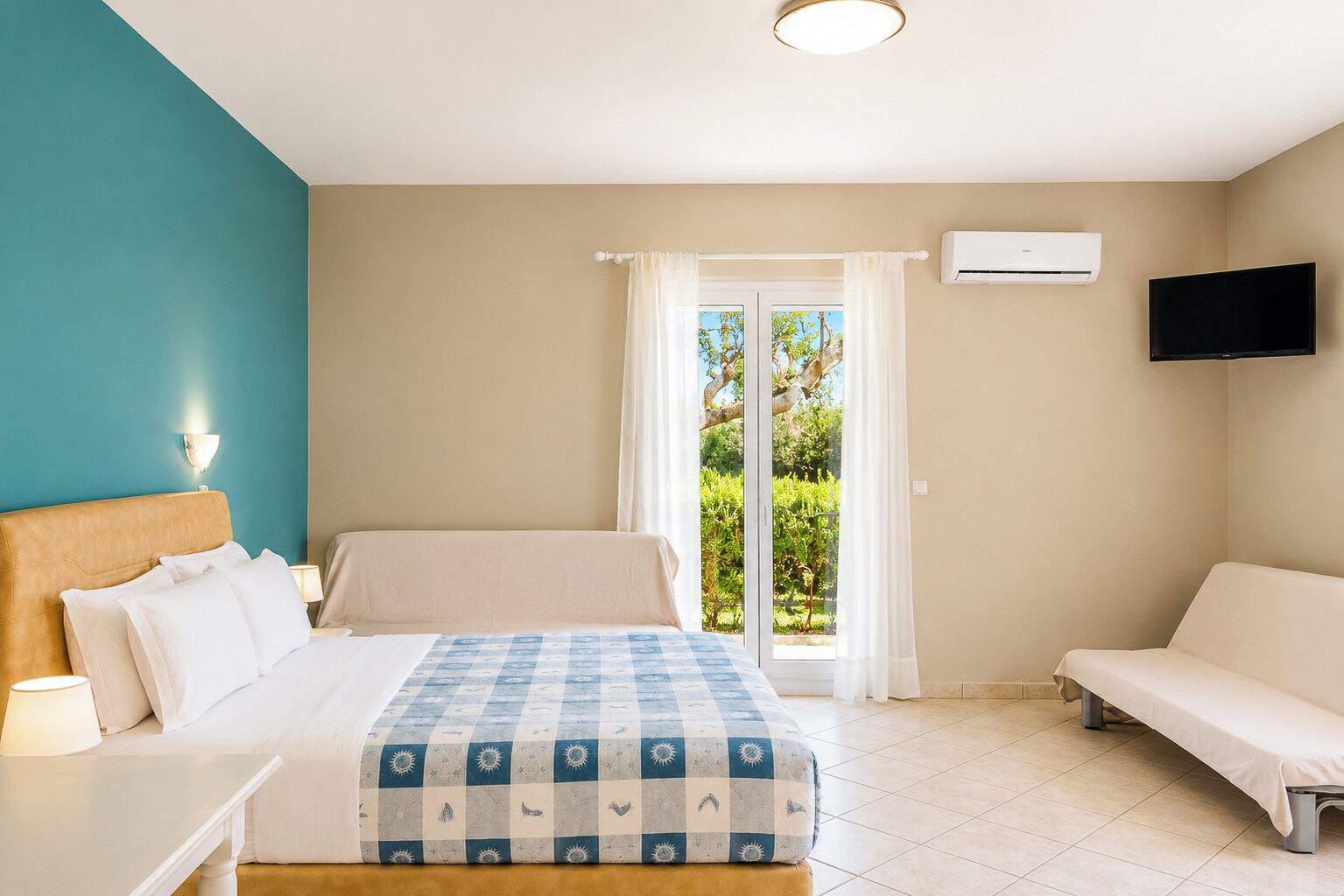 Ein Hotelzimmer mit Bett, einer Sitzecke, einem Fernseher und einer Schiebetür zum Balkon.