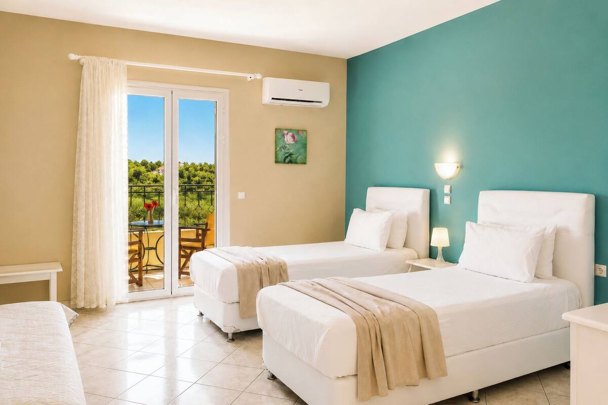 Une chambre d’hôtel avec deux lits, un balcon avec une table et des chaises, et un appareil de climatisation.