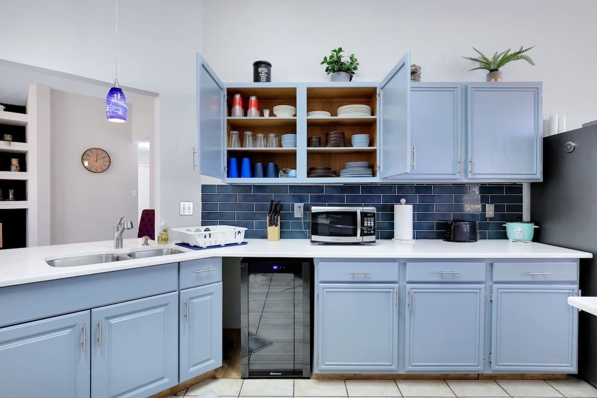 Een moderne keuken met lichtblauwe kastjes, een magnetron en een vaatwasser.
