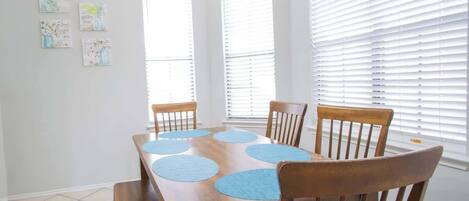A dining room with a wooden table, four chairs, and a bench. There are four wall-mounted light fixtures and a chandelier.