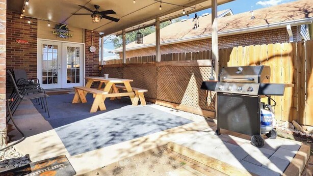 Ein Garten mit Grill, Holztisch und Stühlen.
