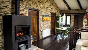 Um quarto com paredes de pedra, lareira, portas de madeira e um espaço de jantar com mesa e cadeiras.