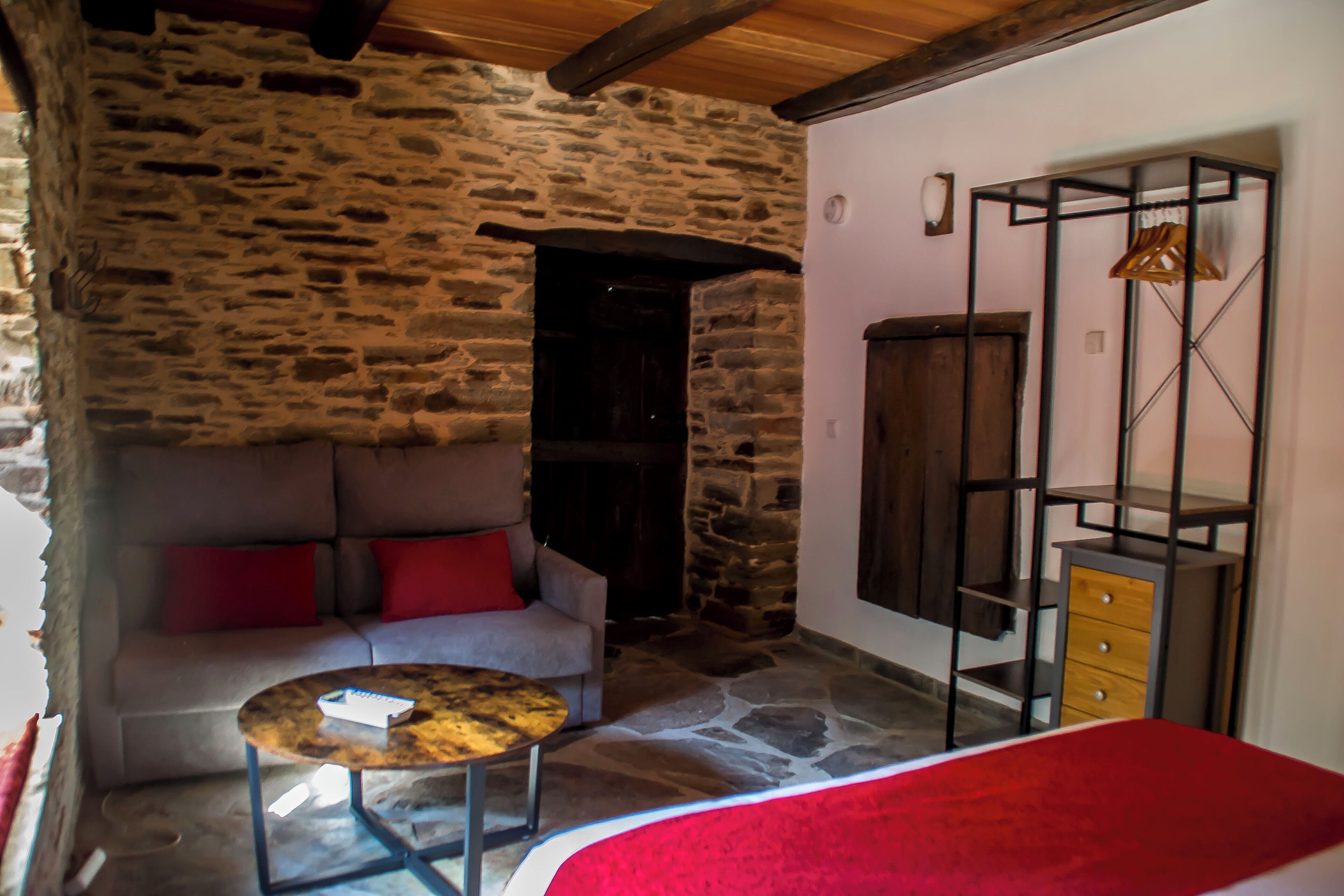 A stone-walled room with a sofa, a small round table, and a wooden cabinet.