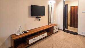 Un bagno moderno con un mobile bagno in legno, uno specchio, una TV a schermo piatto e una porta che dà su un'altra stanza.
