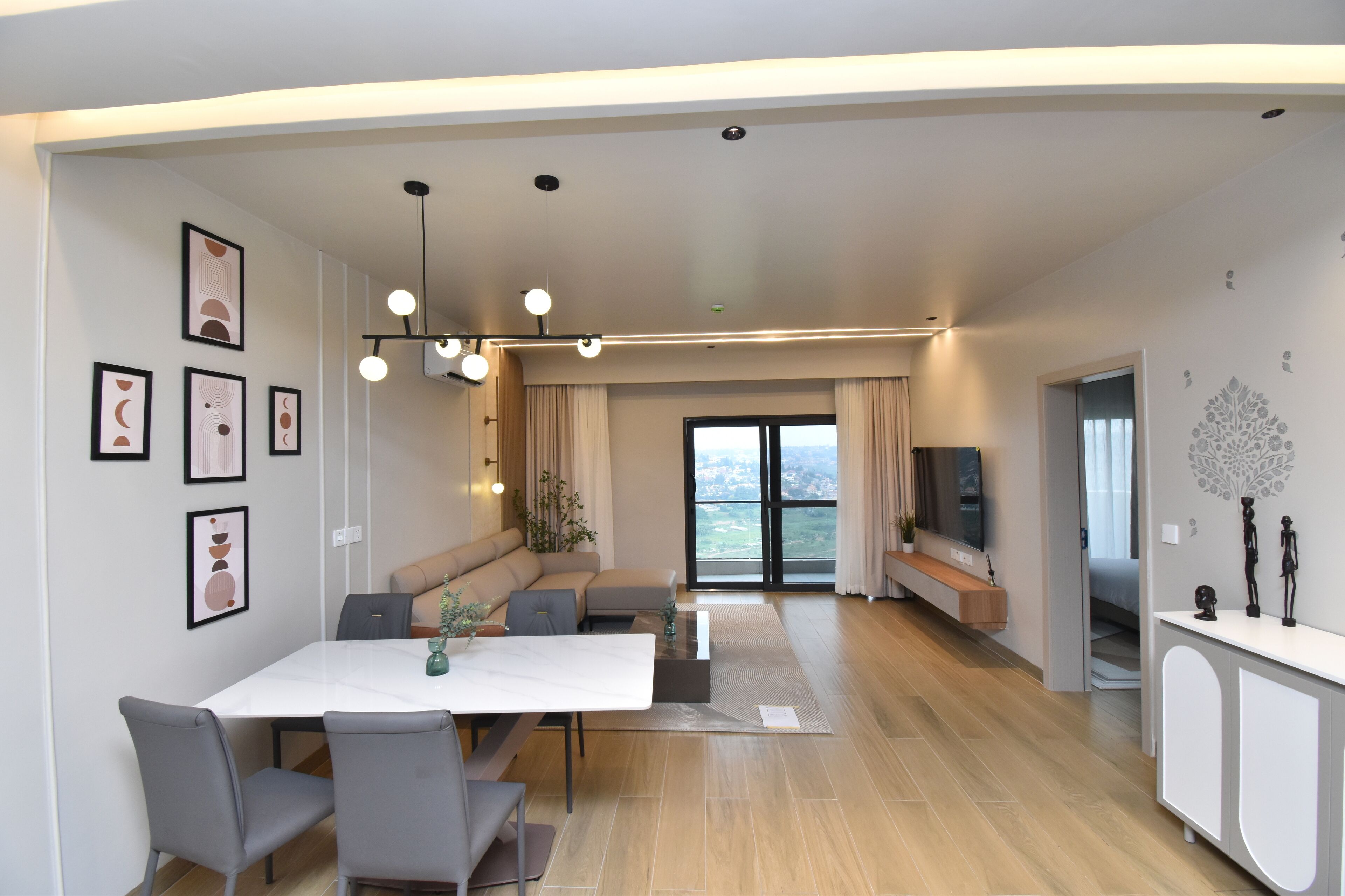 A modern living room with a dining area, a sofa, a TV, and a decorative wall piece.