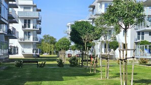A modern apartment complex with multiple balconies, a well-maintained lawn, and trees. - Apartament Luxe w Kołobrzegu - 365PAM (Kolobrzeg)
